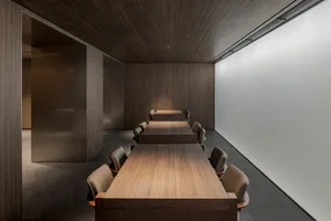 Formal conference room with wooden floors and walls, featuring a large dining table and chairs arranged for meetings and discussions