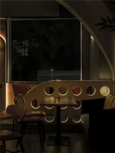 Cozy restaurant dining area with wooden furniture, a bar, and potted plants, featuring ample seating and warm lighting