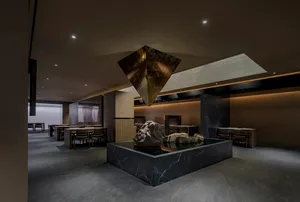 燈光柔和的餐廳內部，以石雕為中心藝術品，周圍環繞桌椅，營造溫暖而樸實的氛圍