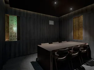 光線昏暗的辦公空間，置有木桌及四張椅子，佔據房間大部分寬度