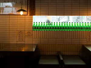 A cozy bar area in an Asian restaurant with a brick wall, green bottles, and comfortable seating for patrons
