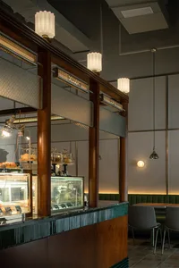 Inviting cafe interior with a counter, dessert display case, and two chairs, featuring a warm and welcoming atmosphere