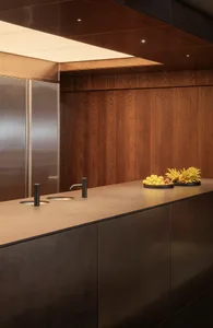 Warm kitchen with wooden cabinets and countertops, featuring two sinks and fresh fruit on the countertop