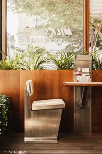 A clean and organized kitchen space with a counter, sink, chairs, and a potted plant, highlighting functional design elements