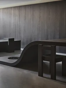 A darkened dining space with a wooden table surrounded by chairs, creating a cozy atmosphere