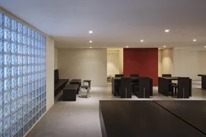 A well-lit restaurant with a red accent wall, wooden tables, and metal chairs, creating a comfortable dining area