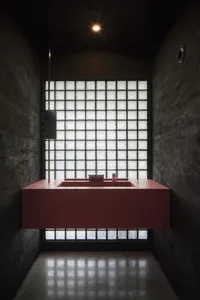 A bathroom with two sinks, one with a mirror, a toilet, and checkered-patterned walls, set in a well-lit and inviting space