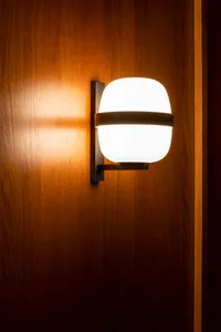 A wooden doorway with a light fixture above, illuminating the surrounding area with a warm atmosphere and visible wood grain texture