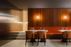 A cozy dining area with two long tables, wooden panel walls, and benches, set up for a meal or gathering