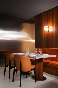A warm and inviting dining area with a wooden table surrounded by chairs, featuring wine glasses and cutlery
