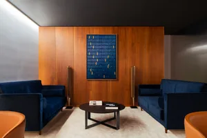 Cozy living room with two couches, chairs, a dining table, and books, set against a wooden wall