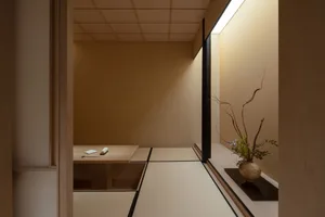 溫暖舒適的客廳區域，配有餐桌、椅子與床鋪，周圍環繞木牆，餐桌上擺放花瓶