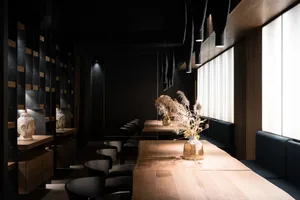 Warm and inviting restaurant interior with a wooden dining table, chairs, vases, and wood elements