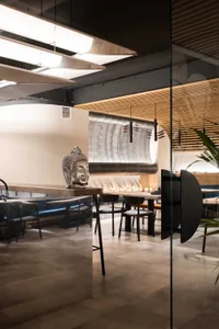 Cozy modern dining space with a large Buddha statue, chairs, and potted plants, featuring clean lines and simplicity