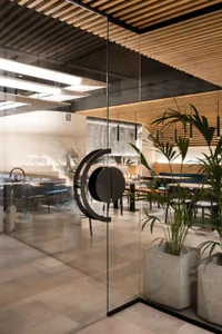 A modern restaurant interior with multiple dining tables, chairs, and potted plants creating a welcoming atmosphere
