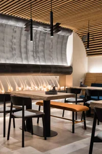 A modern restaurant dining area with multiple tables and chairs, featuring a mix of wood and metal elements, creating an inviting and comfortable atmosphere