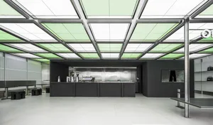 Industrial kitchen with a black countertop, two sinks, and modern appliances, set against a large window