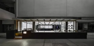 Bright modern cafe with concrete walls, a large window, and a dining table surrounded by chairs