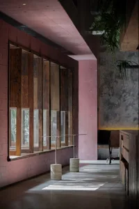 Modern interior space with a large window in a brick wall, featuring multiple panes of glass and a minimalist aesthetic, with two chairs and a potted plant