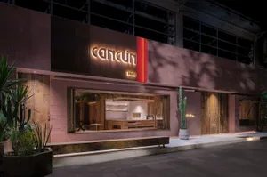 粉色外觀的現代零售店，紅色招牌，以及燈光明亮的室內，設有桌椅供瀏覽家居裝飾品