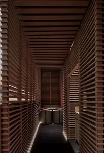 A modern kitchen dining space with wooden walls, a sink, and trash cans, featuring a functional and cozy atmosphere