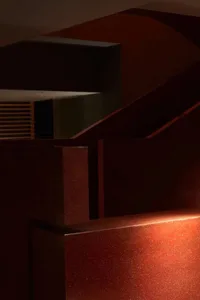 A dimly lit staircase in a house with red brick stairs, leading downwards