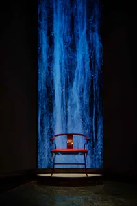 A serene scene with a red chair in front of a waterfall, set against a wooden surface, in a peaceful atmosphere