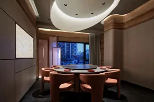 A well-lit dining area with a wooden table and leather chairs, visible outside views of a busy street