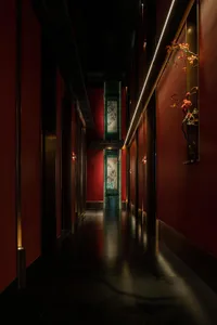 A long hallway with red walls, dark wood flooring, and decorative doors with screens, creating an elegant and sophisticated atmosphere