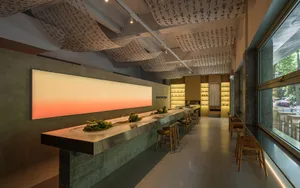A modern Asian restaurant with a long wooden bar, oriental decorations, and multiple bowls on the counter