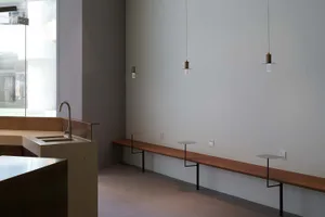 Empty kitchen dining space with a bench and sink, illuminated by pendant lights