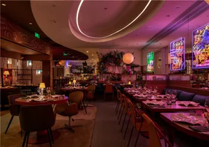 A cozy restaurant dining area with wooden tables, chairs, and wine glasses, set in a warm and inviting atmosphere