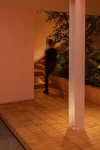 A calm residential staircase with wooden steps and a brown tint, featuring a person at the bottom