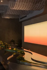 Warm dining area with a long table, potted plants, and various food items, creating a cozy atmosphere for gatherings and meals