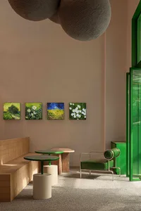 Cozy cafe with green walls, tables, and a couch, featuring artwork and comfortable seating options