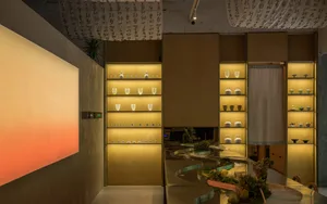 展示空間陳列酒杯、杯子、碗盤與花瓶置於桌上及吊掛天花板，溫暖氛圍融入木質元素