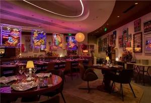Elegant dining space with seating areas, tables, artwork, and warm lighting