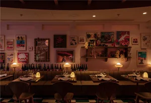 Cozy dining area with wooden tables, chairs, and wine bottles, set in a warm and inviting atmosphere