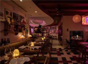 A cozy restaurant dining area with a long wooden table and chairs, wine glasses, and a warm atmosphere