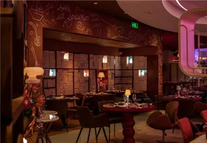 Elegant dining space with wooden tables, chairs, and decorative elements, featuring wine glasses and an inviting atmosphere