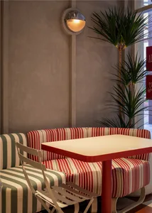 A cozy living area with a red wooden dining table surrounded by striped chairs, creating a warm and inviting space for socializing and meals