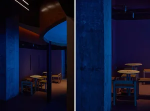 Dimly lit restaurant with wooden walls, multiple dining tables, and benches, creating a cozy atmosphere