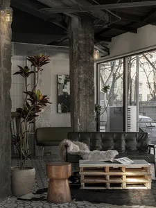 Cozy living space with a couch, chair, and dining table, surrounded by natural light and potted plants