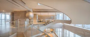 Open modern living area with a spiral glass staircase, minimalist design, and an airy atmosphere