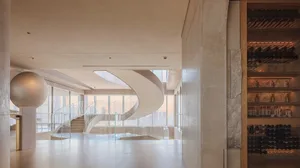 Modern open building with a spiral glass staircase, steel structure, and natural light from windows