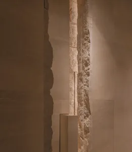 Dark interior space with a stone wall and a concrete wall, featuring a textured and smooth surface respectively