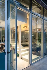 Open living area with white walls and floors, featuring potted plants and decorative vases, with bright and inviting atmosphere and ample natural light