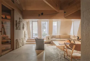 Cozy open living area with a couch, chairs, dining table, and natural light from a window