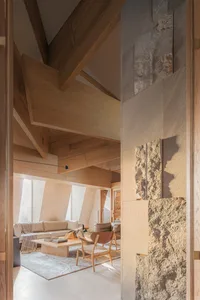 A warm and inviting living space with wooden floors and walls, featuring two couches, a chair, and a dining table, with decorative items scattered throughout