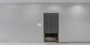 A minimalist hallway with a gray curtain-drawn doorway on a white wall, with no other visible features
